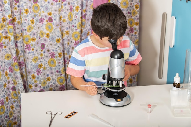 Niño caucásico examinando la preparación bajo el microscopio