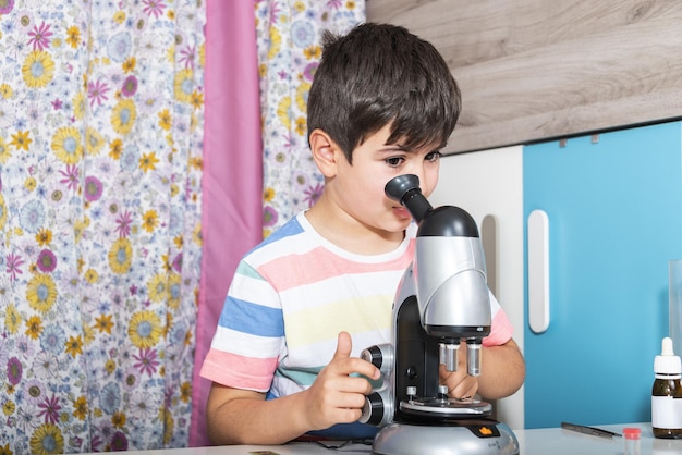 Niño caucásico examinando la preparación bajo el microscopio