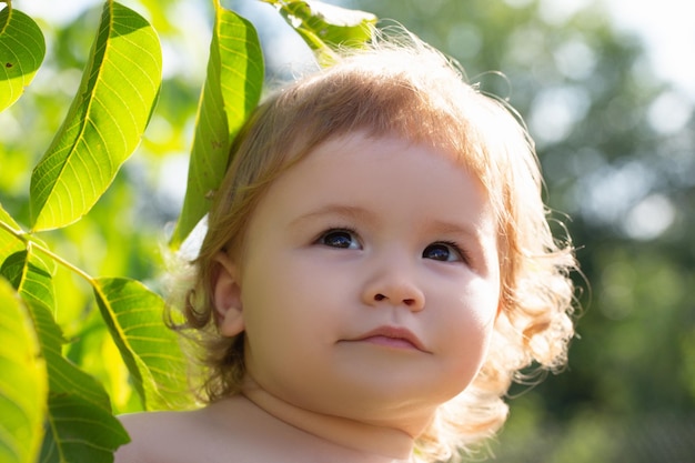 Niño caucásico con hojas verdes retrato de cerca cara de bebé para niños en el parque natural
