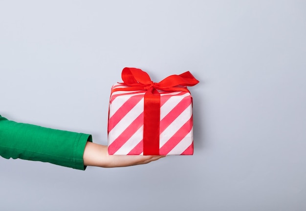 Niño caucásico mano sostiene caja de regalo sobre fondo azul Copiar espacio para diseño o texto Banner Navidad Año Nuevo plantilla de maqueta