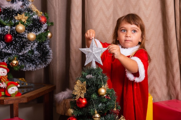 Niño caucásico organizar decorar el árbol de navidad con el concepto de ideas festivas navideñas divertidas y alegres