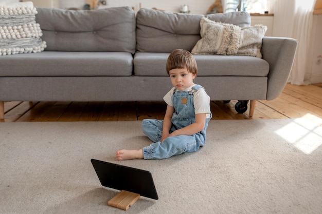 Niño caucásico preescolar mira dibujos animados en tablet pc en casa