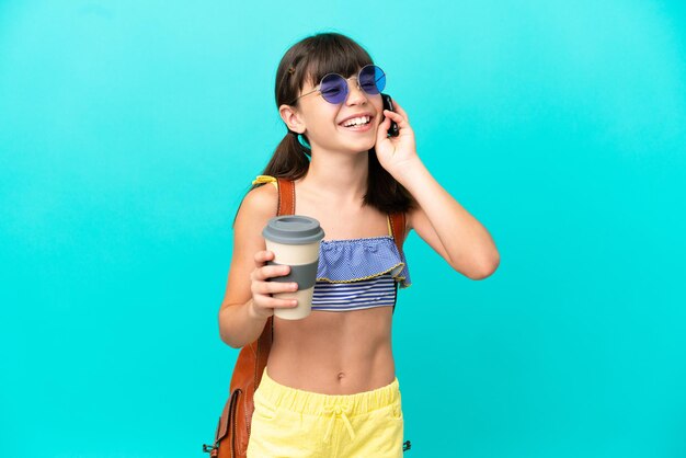 Niño caucásico que va a la playa aislada sobre fondo azul con café para llevar y un móvil