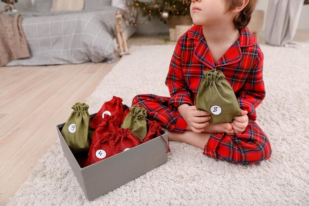 Un niño caucásico sostiene una bolsa con el número 8 del calendario de adviento