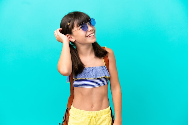 Un niño caucásico yendo a la playa aislado de fondo azul pensando en una idea