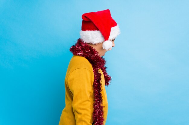 Niño celebrando el día de Navidad vistiendo un sombrero de santa aislado gritando hacia un espacio de copia