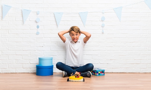 Niño celebrando su cumpleaños con un pastel infeliz y frustrado con algo.