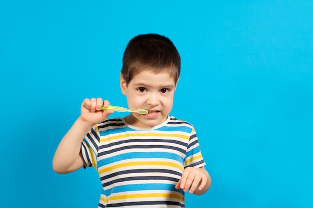 Un niño se cepilla los dientes con un cepillo de dientes verde.