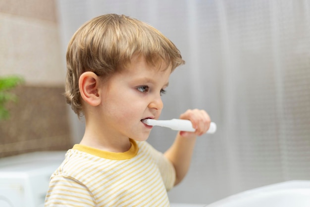 Niño con un cepillo de dientes eléctrico en el baño