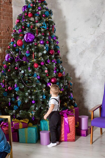 niño cerca del árbol de navidad con un regalo