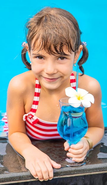 Un niño cerca de la piscina toma un cóctel.