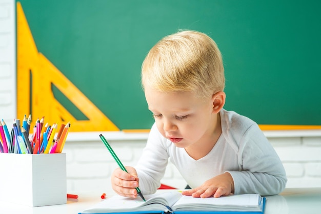 Niño cerca de la pizarra en el aula de la escuela Primer día de clases Tutoría individual Educación