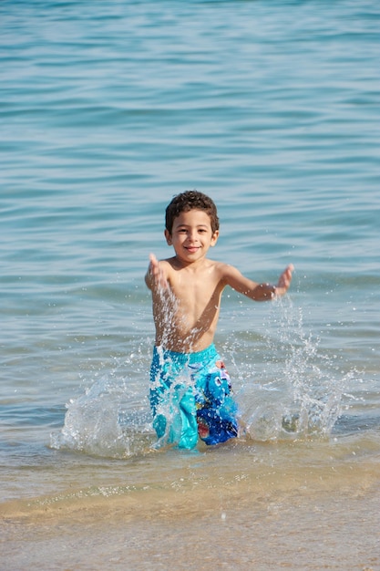 Un niño chapotea en el agua de la playa.