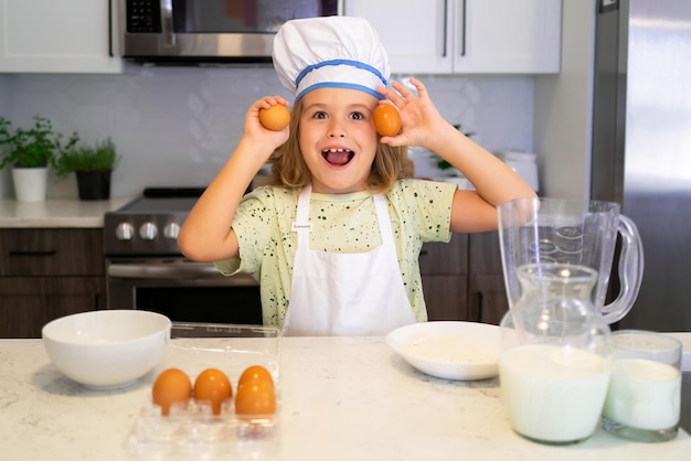 Niño chef cocinero Niño divertido parado en la mesa de la cocina diviértete horneando haciendo panadería preparando comida en casa kithen Comida saludable Pequeño chef preparando comida saludable