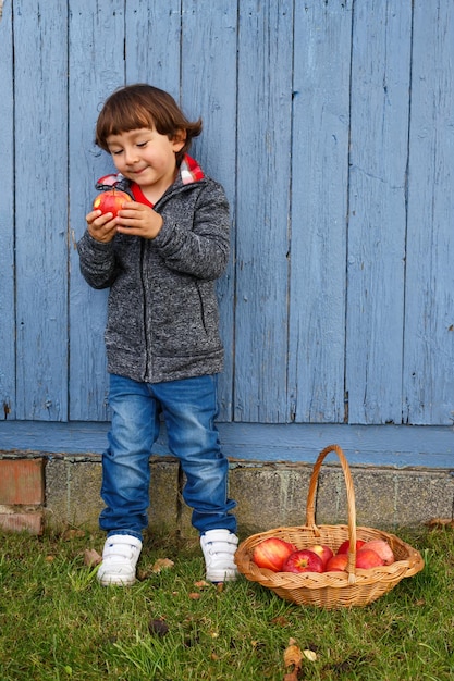 Niño chico comiendo manzana fruta cuerpo completo al aire libre copyspace otoño otoño saludable