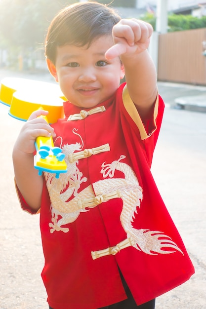 Niño chino joven sonriente y feliz en traje de año nuevo chino vestido