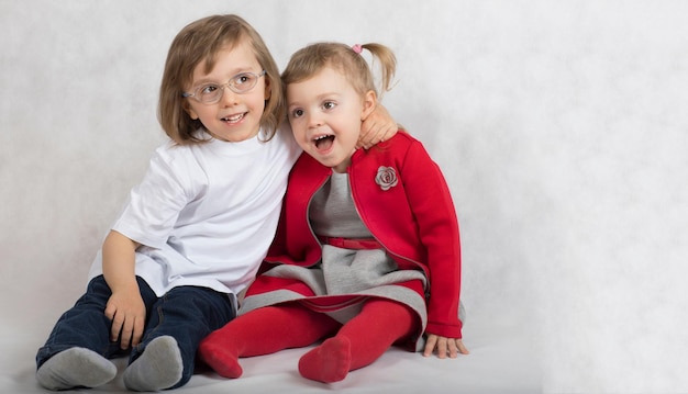 Un niño de cinco años y una niña de 2 años se quedan juntos. fondo gris.