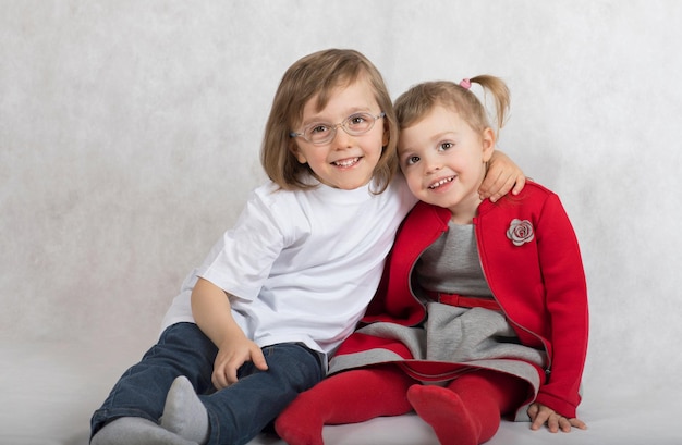 Un niño de cinco años y una niña de 2 años se quedan juntos. fondo gris.