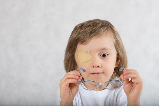 Niño de cinco años con un ojo cubierto por una almohadilla para los ojos y con anteojos.