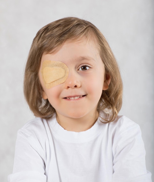 Niño de cinco años con un ojo cubierto por una almohadilla para los ojos y con anteojos.