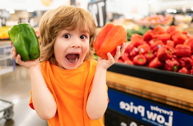 Foto un niño cliente feliz sostiene el carrito de compras en la tienda de comestibles del supermercado