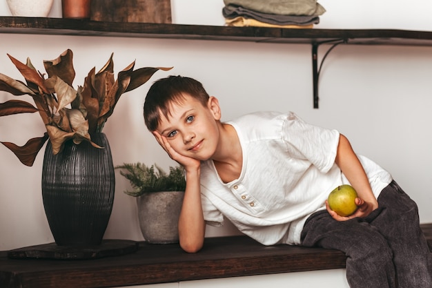 Foto un niño en la cocina con una manzana verde. concepto de comida sana para niños