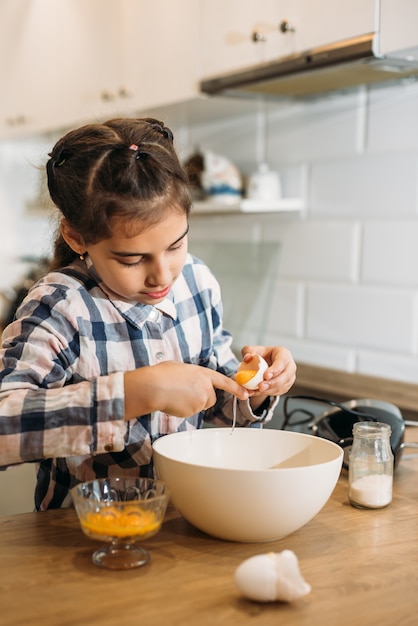 Foto niño en una cocina. niña con masa. niño con camisa azul y sombrero de shef blanco