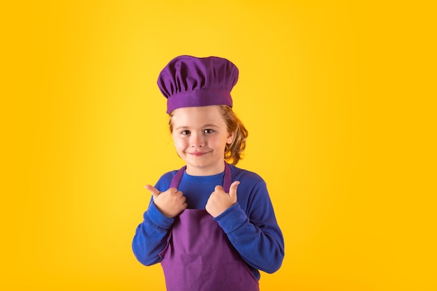 Niño cocina pequeño chef prepara comida Kid boy en sombrero de chef y delantal sobre fondo amarillo estudio aislado