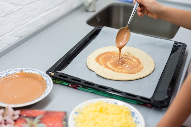 niño cocina pizza casera, niña hace pizza en casa