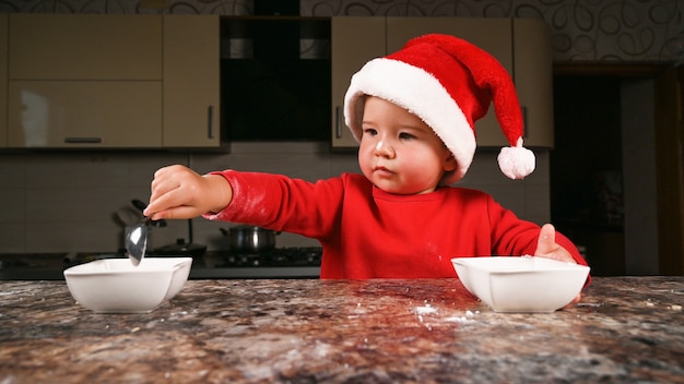 Niño en la cocina con un sombrero de Navidad. Foto de alta calidad