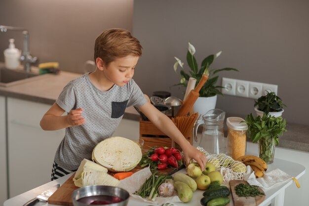 Foto un niño cocinando con verduras en la cocina