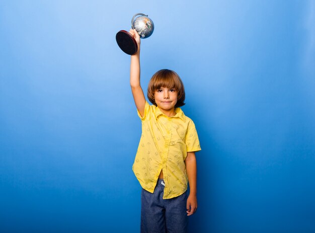 Niño, colegial, 7 años, colegial, con, un, recuerdo, globo, en, el suyo, manos, sonriente, en, un, fondo azul