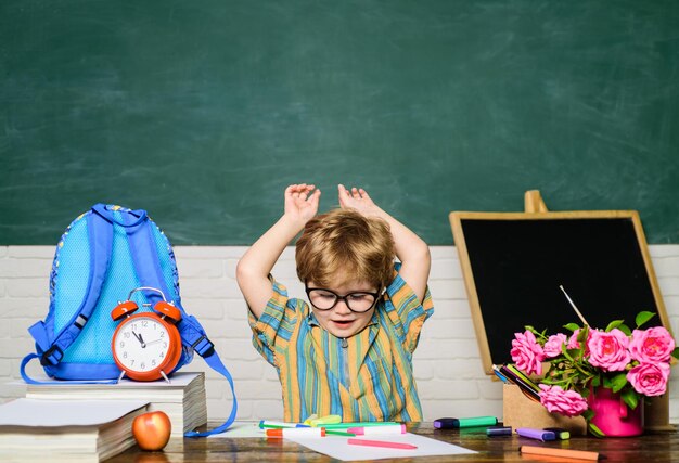 Niño colegial disfruta de aprender a escribir estudiante de la escuela primaria en el lugar de trabajo lindo niño chico haciendo