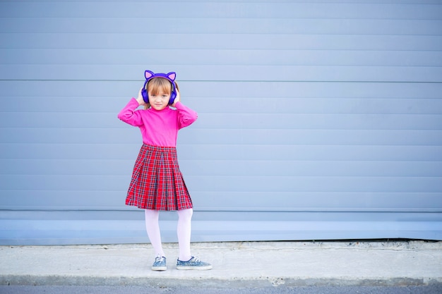 Un niño, un colegial, escucha música con auriculares inalámbricos brillantes. Auriculares Bluetooth modernos