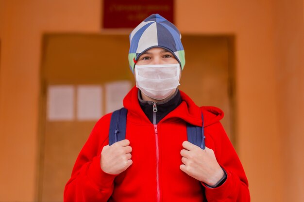 Niño colegial sale de la escuela con máscara protectora