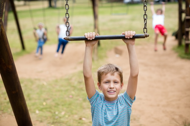 Niño colgado de un equipo de juego en el parque