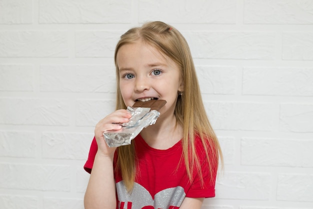 un niño come una barra entera de chocolate con una sonrisa en su rostro