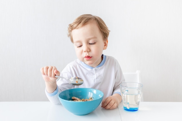 El niño come con una cuchara en casa el concepto de alimentación y nutrición para niños.