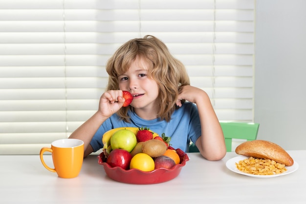 El niño come frutas orgánicas de fresa verduras saludables con vitaminas concepto de nutrición infantil adecuado