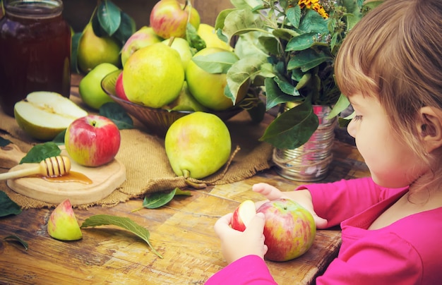 El niño come miel y manzanas. Enfoque selectivo