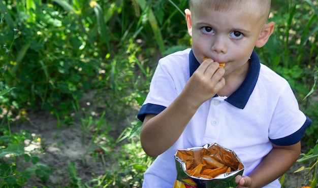 El niño come papas fritas de un paquete