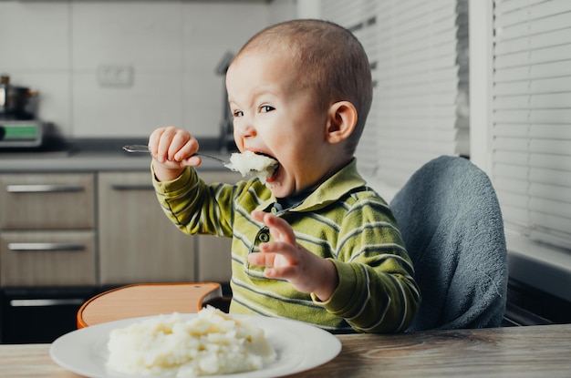 El niño come puré de patatas.