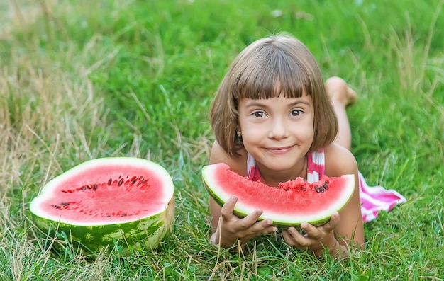 Niño come una sandía en el jardín.