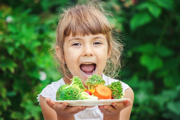 El niño come verduras. Foto de verano Enfoque selectivo