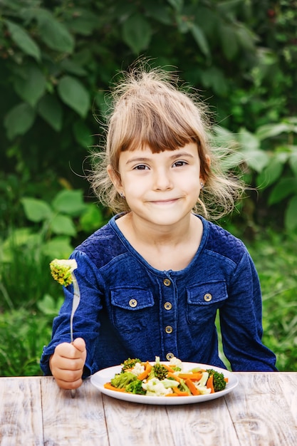 Foto el niño come verduras. foto de verano enfoque selectivo