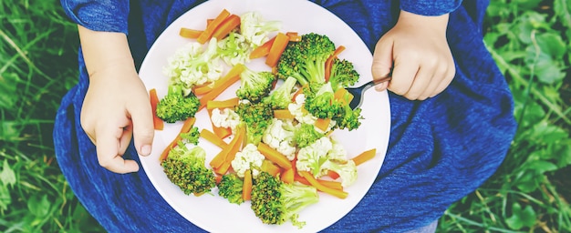 El niño come verduras. Foto de verano Enfoque selectivo