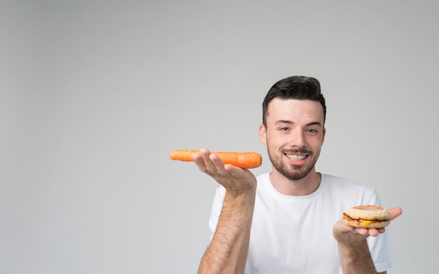 Niño come una zanahoria y una hamburguesa