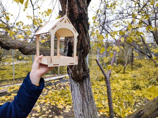 Niño con comedero para pájaros de madera en el concepto de conservación de la naturaleza del jardín de otoño