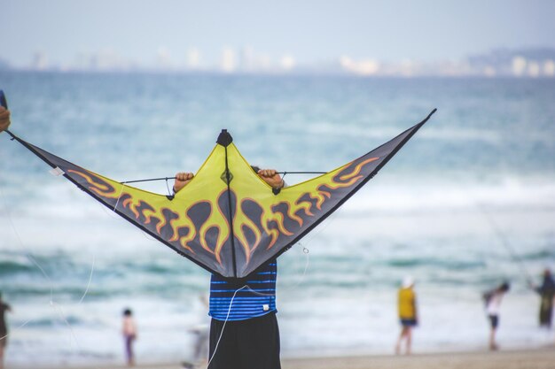 Foto niño con una cometa de pie en la playa