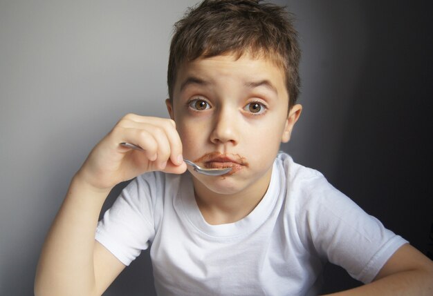 Foto niño comiendo chocolate lindo niño feliz cubierto de chocolate